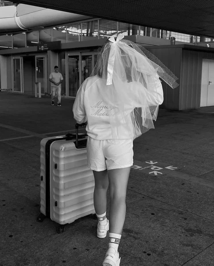 Future bride with suitcase travels for her hen do, wearing bridal gifts from Gigi & Olive Brand