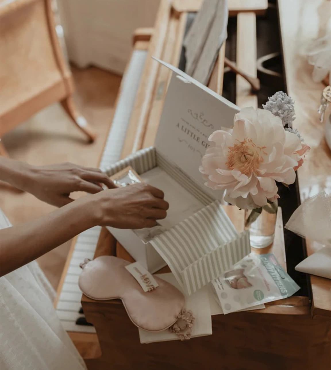 A close up of bride's hands packing the gift box with chic wedding presents for her future bridesmaids.