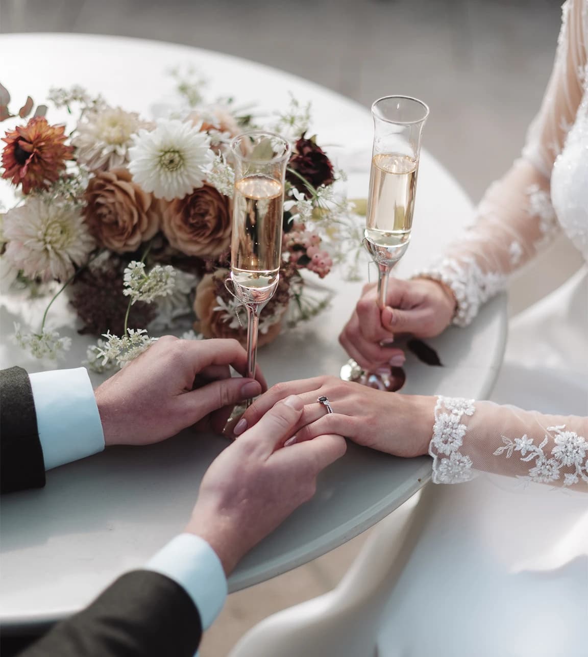 A close up of groom and bride holding hands with champagne on their wedding day