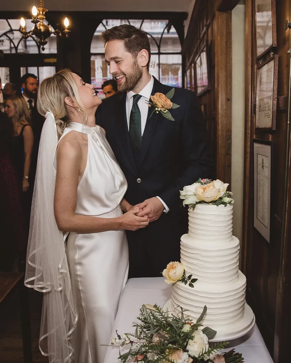 Bride and groom embracing next to their wedding cake