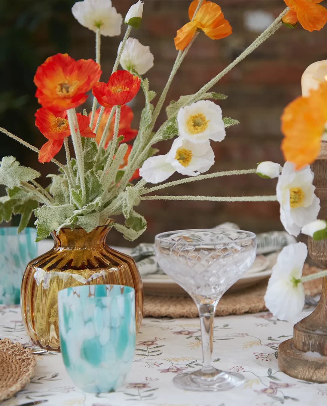 Summer tablescape with red poppies features luxury glassware wedding presents: colourful tumblers and crystal champagne coupes.