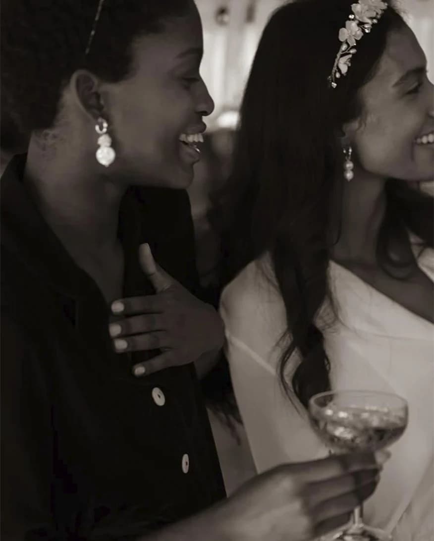 Bride with her friend in matching PJs hold a glass with drink to celebrate bride's hen do.