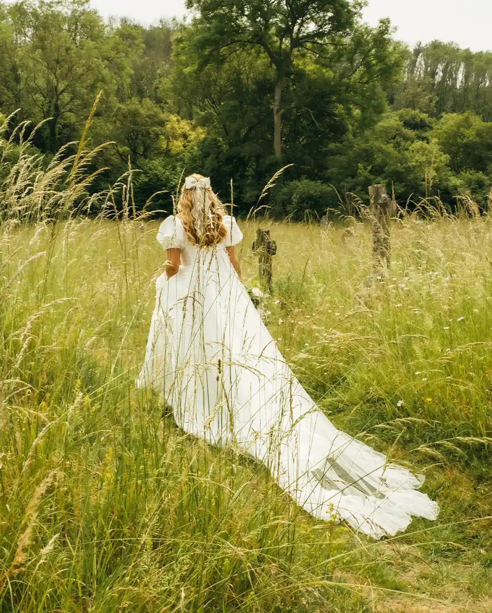 bride in a whimsical wedding dress walking into a garden with long grass