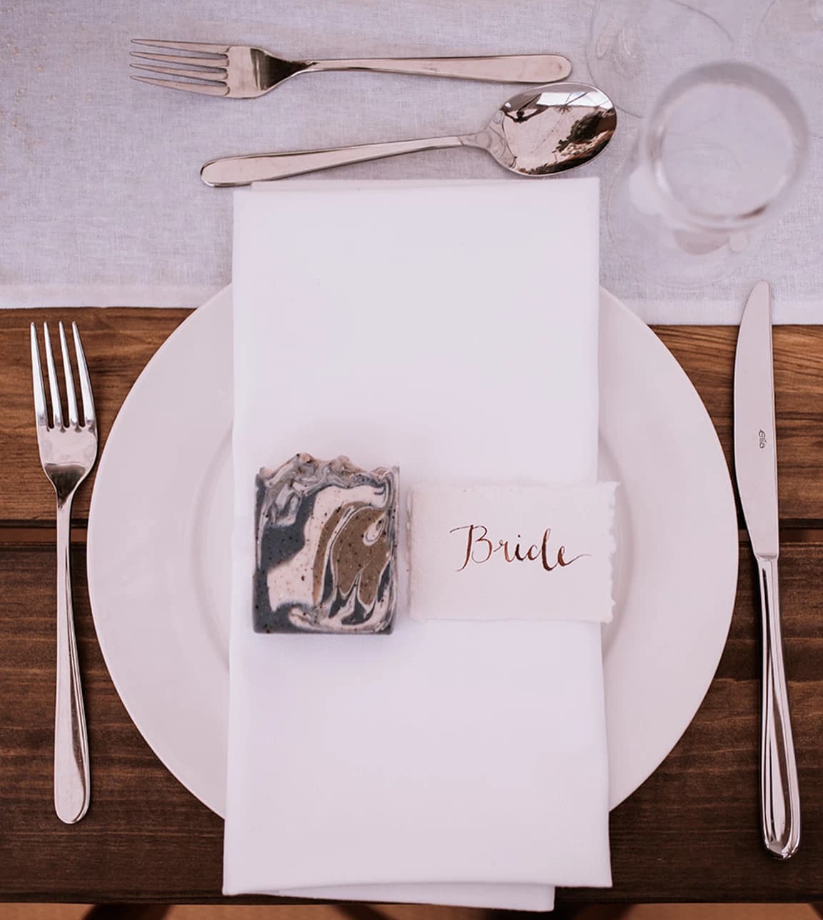 A wedding favour, a natural soap, is placed on a plate with 'Bride' tag next to it.